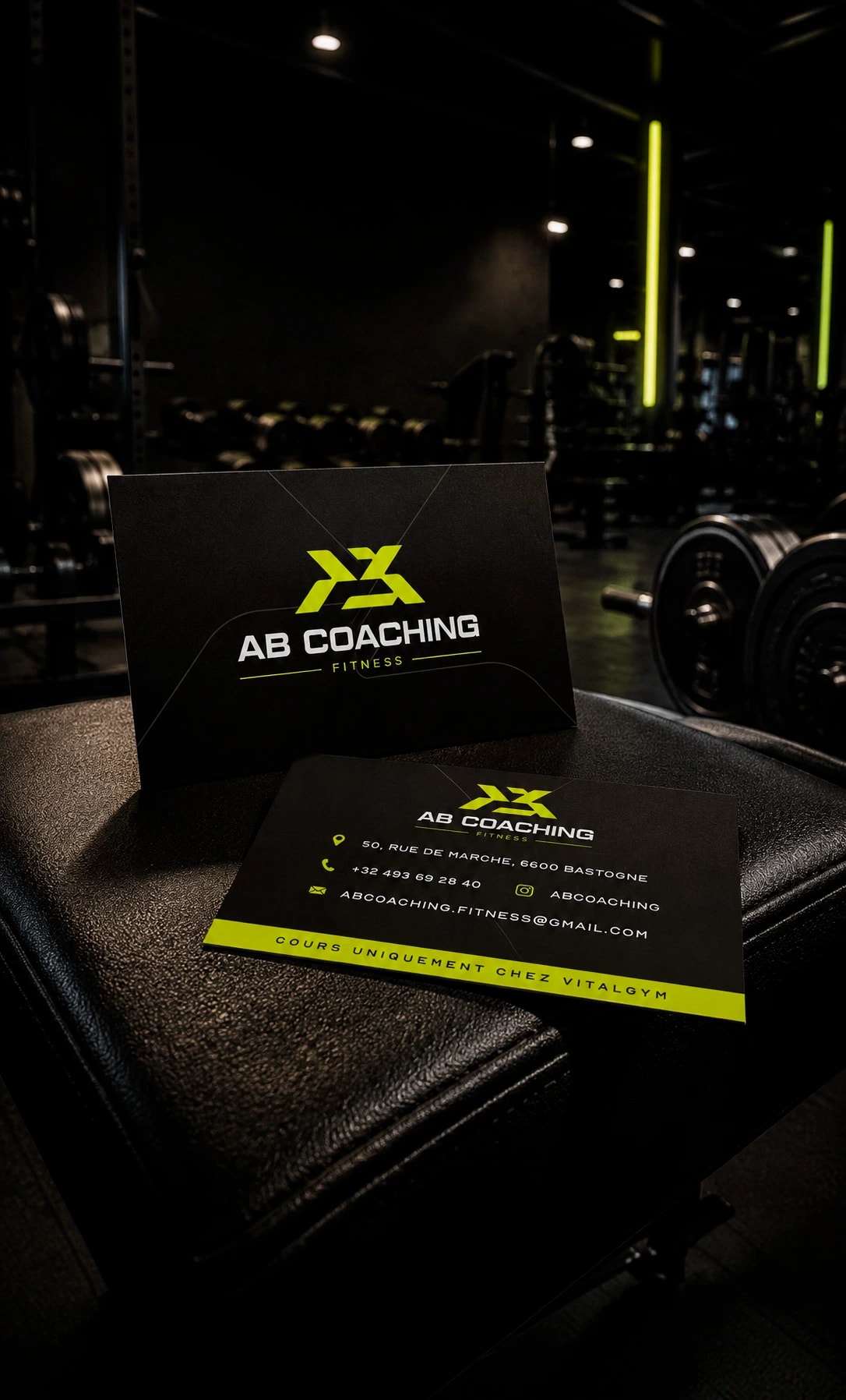 Cartes de visite AB Coaching Fitness, noir et jaune fluo, posées sur un banc de musculation